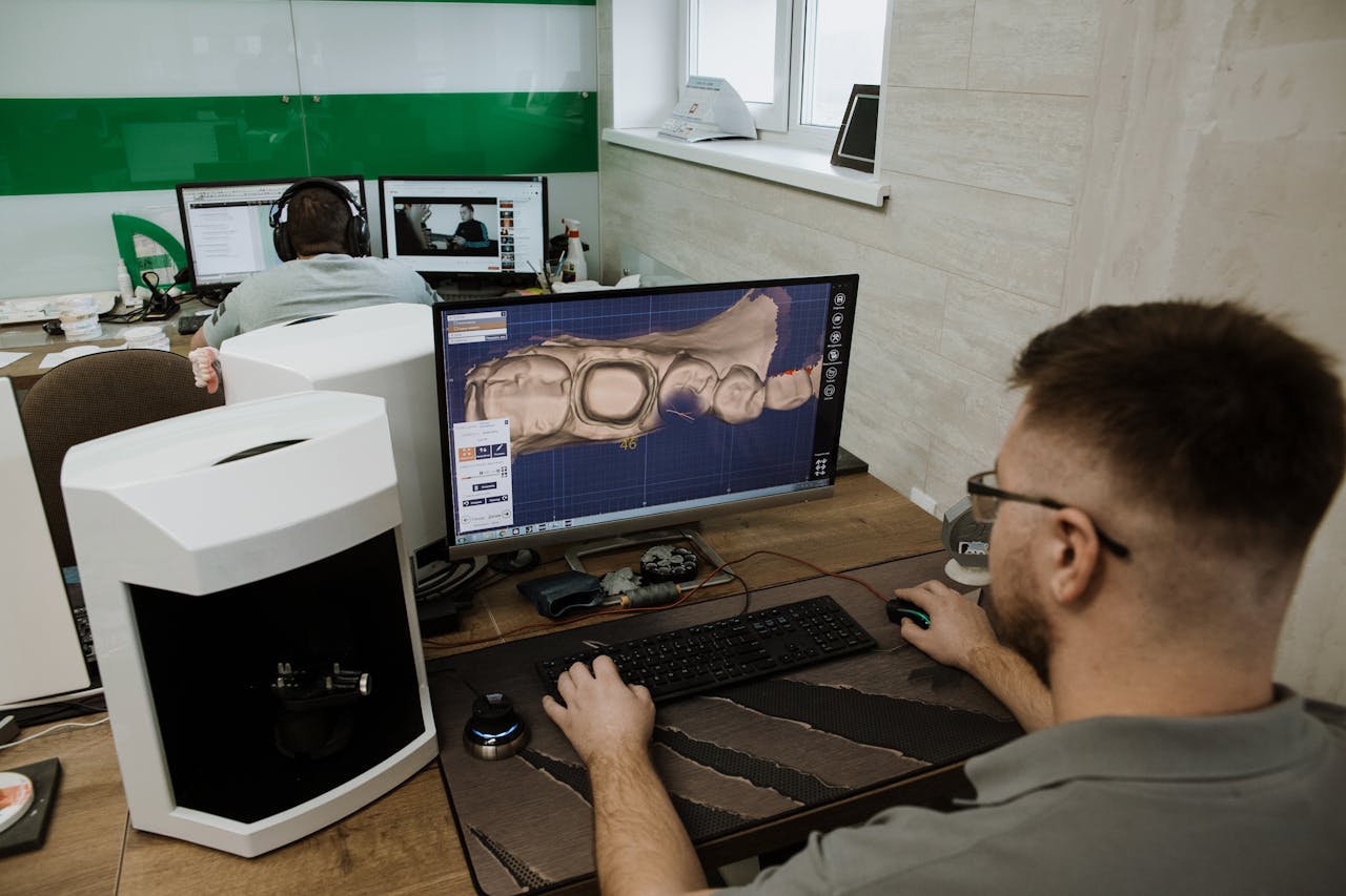 Dental technician using CAD software to design prosthetic teeth in a modern clinic.